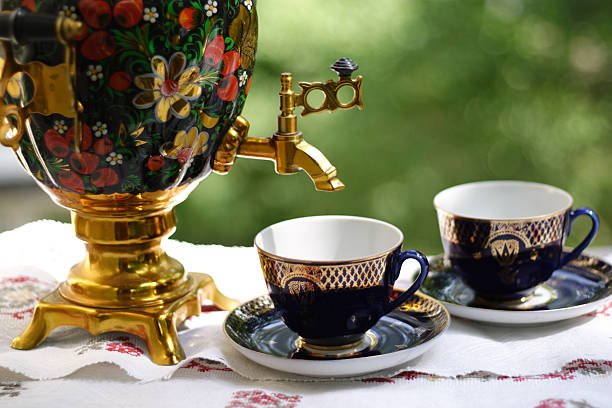 Ornate traditional Russian samovar with brass and copper detailing, accompanied by glasses of black tea and jam, representing the communal Russian tea traditions and cultural ceremonies that emphasize warm hospitality and extended conversation