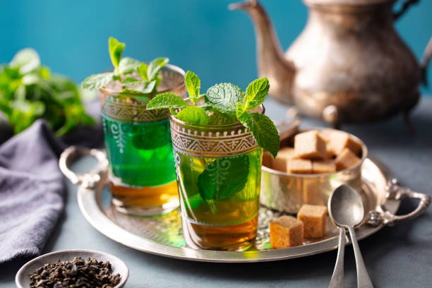Traditional silver Moroccan teapot pouring mint tea from height into ornate glasses, demonstrating the authentic Moroccan mint tea ceremony and tea traditions that showcase hospitality and cultural heritage