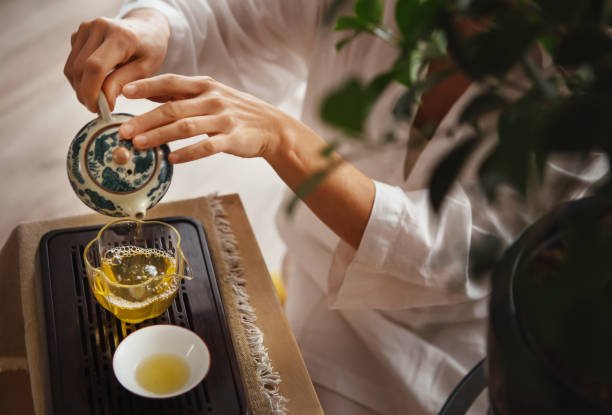 Close-up of small clay teapot and cups used in Chinese gongfu tea brewing method, demonstrating the precise gongfu tea traditions with multiple small servings arranged on wooden tea tray