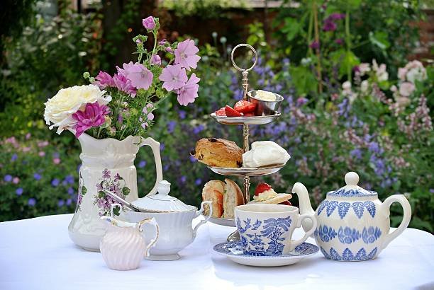 Elegant three-tiered silver stand with delicate finger sandwiches, scones with jam and cream, and petit fours, showcasing the refined British afternoon tea tradition that emphasizes social connection and culinary presentation